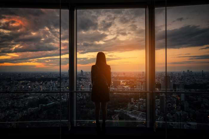 日没時の展望台から景色を眺めている旅行者女性の後姿